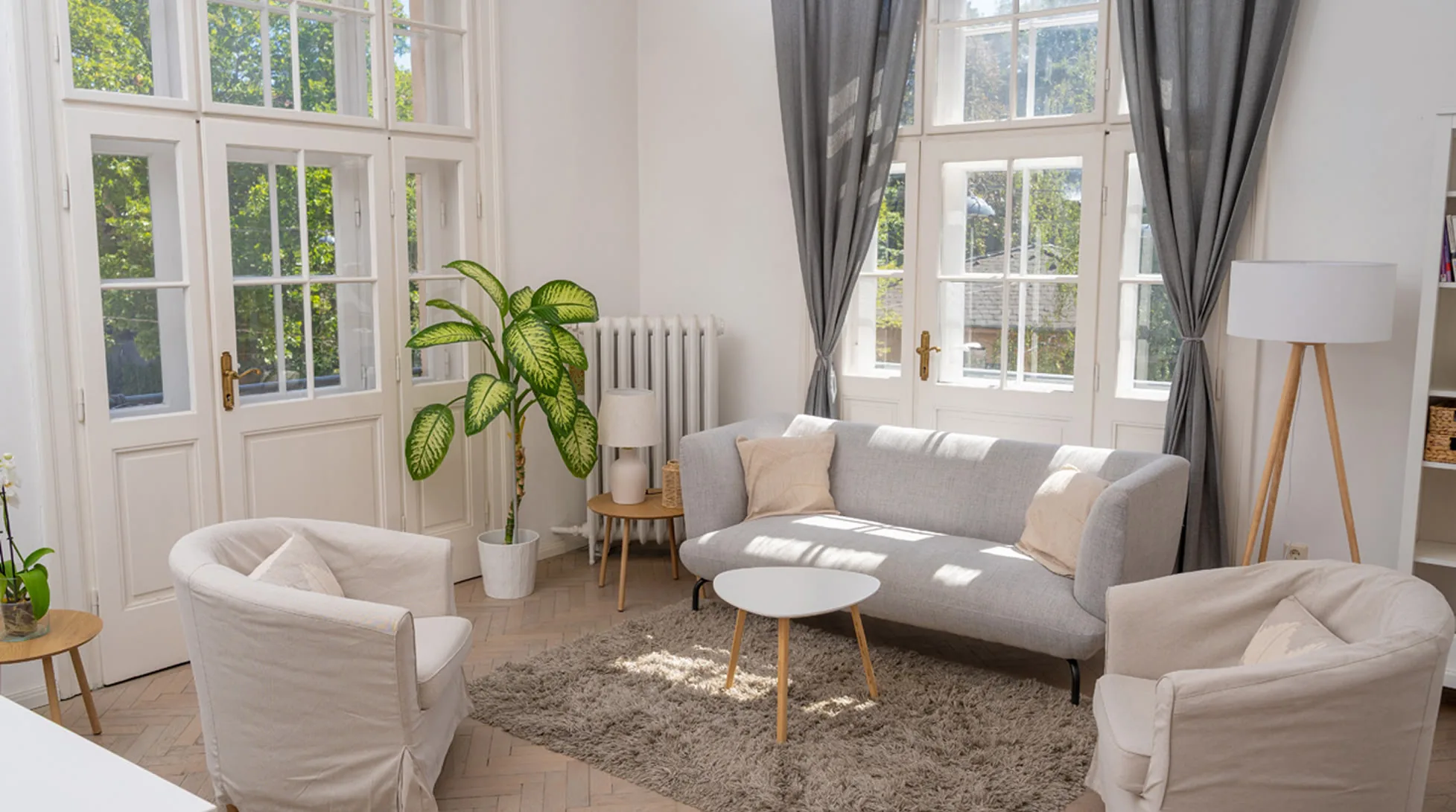 Heller Therapieraum der Praxis in Wien-Hietzing mit Sofa, Sesseln und großen Fenstern.